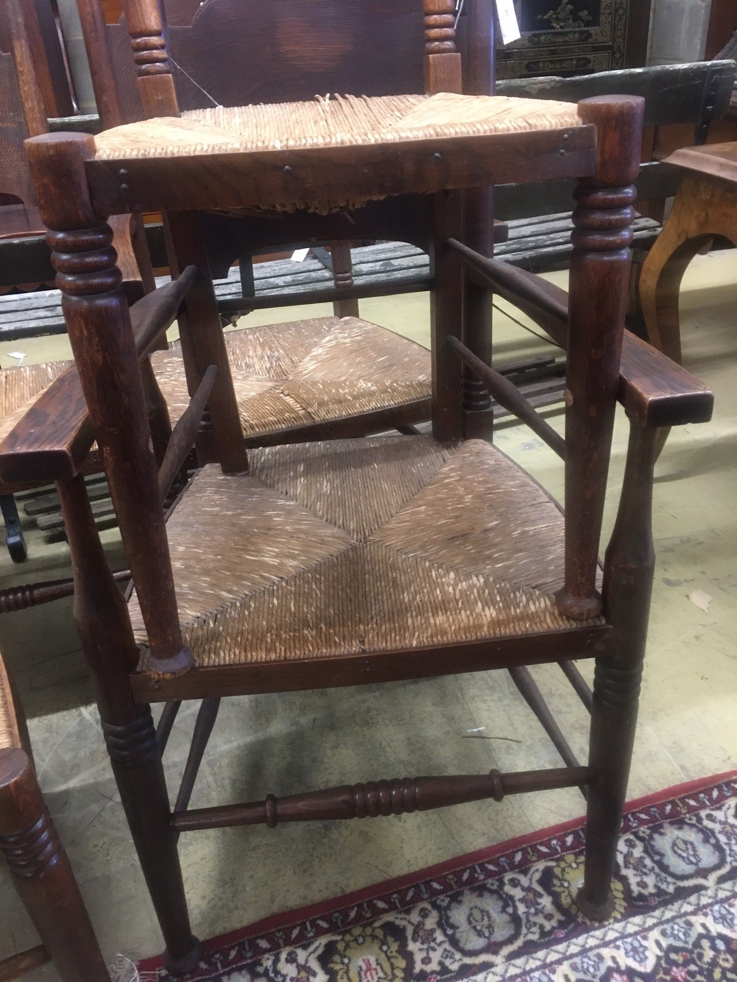 A set of six Arts & Crafts oak chairs, including a pair of carvers, in the Glasgow School manner by William Birch, High Wycombe, with shaped panels backs, ring turned frames and rush seats, carvers W.58cm D.54cm H.109cm